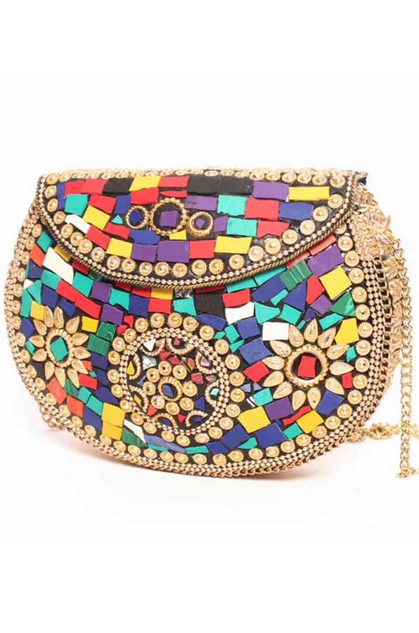 Bolso de latón dorado con piedras de colores decorativas incrustadas, tipo bombonera. Forrado completamente por la zona interior y cierre a modo cofre, es ideal para usar de mano, como clutch de fiesta, o bien con su cadena a modo de bandolera. Es de Valentina del Sur. Precio: 60 €.