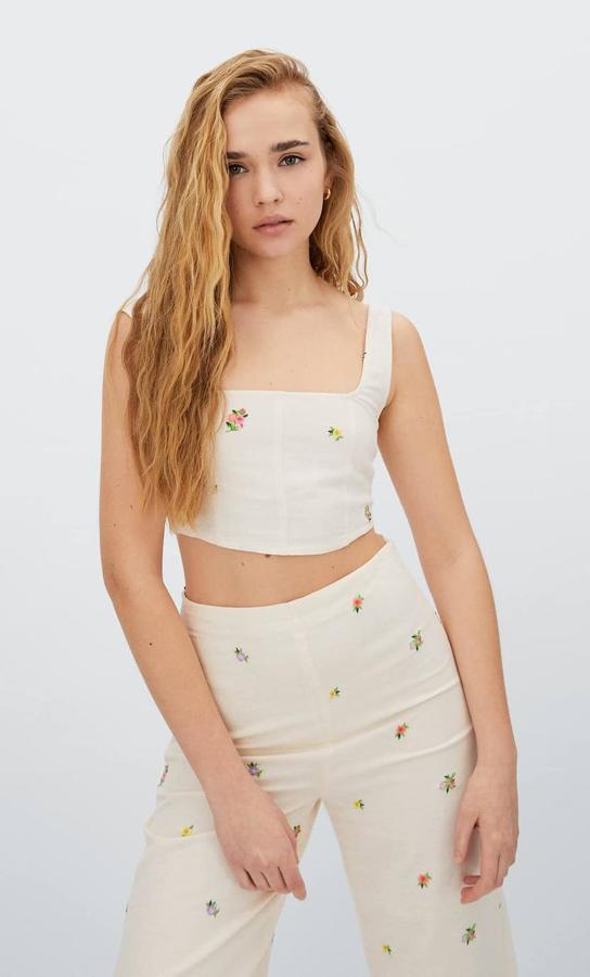 Top tipo corset con escote cuadrado, tirantes anchos, silueta entallada y detalles bordados de flores, de Stradivarius. Puedes comprarlo con descuento a 9,99 euros.