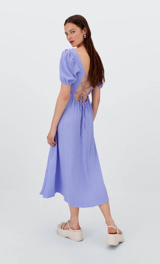 Vestido midi en tejido texturizado color lila, con escote cuadrado, manga corta abullonada, espalda abierta con lazada y abertura en el bajo, de Stradivarius. Lo encontrarás a 29,99 euros.