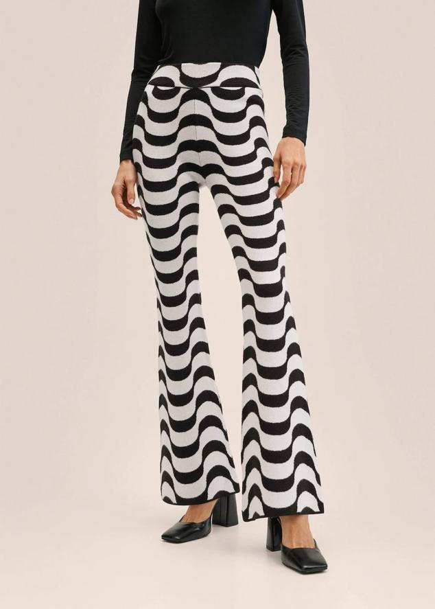 Pantalón flare de punto fino elástico, con tiro alto, bajo acampanado y estampado de ondas bicolor en blanco y negro, de Mango. Cuesta 19,99 euros, rebajado.