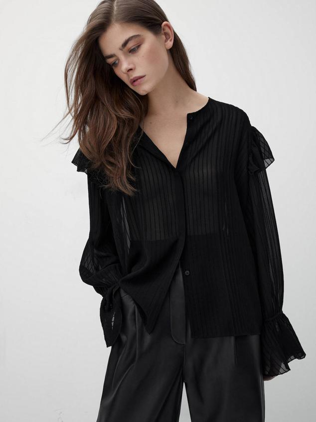 Camisa de estructura devoré con cuello redondo, manga larga, cierre de botones a tono y detalles de volantes, en negro. Cuesta 25,95 euros, con descuento.