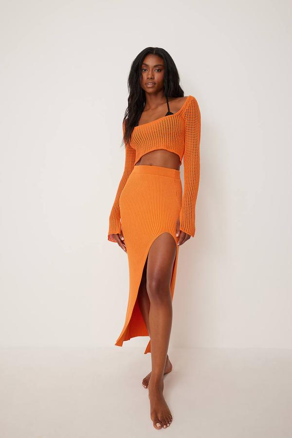 Falda midi de punto acanalado con silueta ajustada al cuerpo, tiro alto y detalle de abertura en el bajo, color naranja, de NA-KD. Su precio es de 57,95 euros.