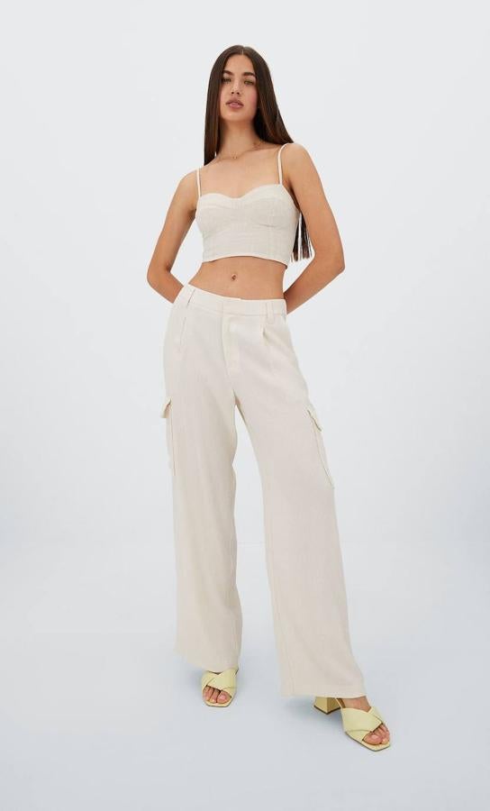 Pantalón cargo de vestir con tejido fluido, detalle de pinzas delanteras, tiro alto, pernera amplia y bolsillos de plastrón con solapa laterales, color crudo, de Stradivarius. Los encontrarás en rebajas por 9,99 euros.