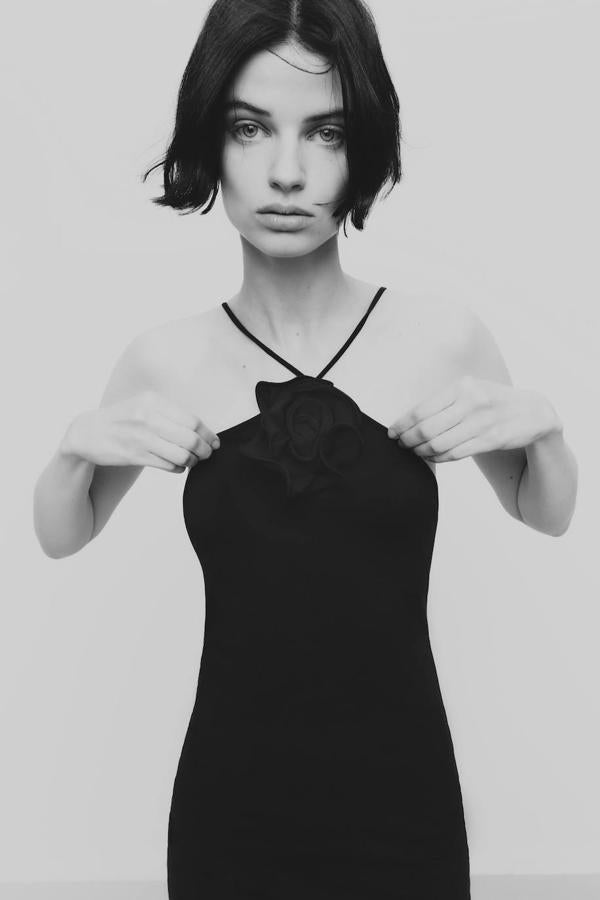 Vestido corto de cuello halter con tirantes finos y detalle de flor en relieve en el escote, color negro. Cómpralo a 19,95 euros.
