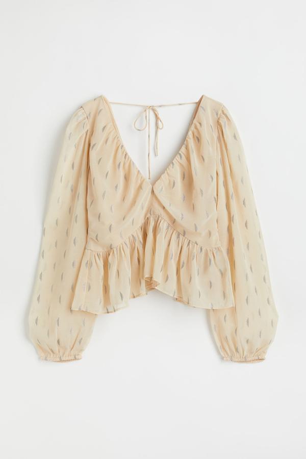 Blusa corta con tejido vaporoso y diseño jacquard. Tiene un escote pronunciado con fruncidos en la zona frontal y trasera. Es de H&M. Precio: 24,99 €.