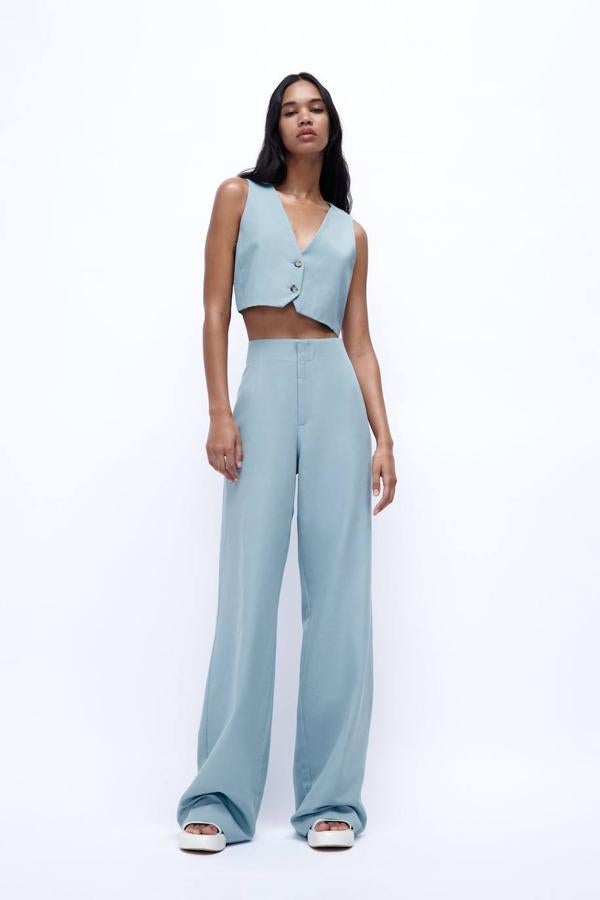 Traje en tejido mezcla de lino color azul claro, compuesto por chaleco de diseño cropped y pantalón full length de tiro alto con pernera ancha, de Zara. El precio de las prendas es de 25,95 euros y 29,95 euros, respectivamente.