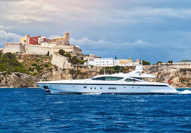 Waterside view of the Dalt Vila of Ibiza and motor yacht. The fortification of the city were listed as a UNESCO Heritage Site in 1999. Balearic Islands, Spain