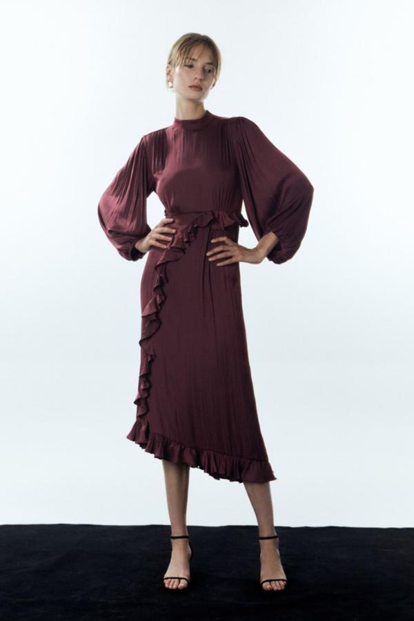 Vestido largo y fluido con cuello alto y manga amplia con detalla de volante en el frontal. Cierre trasero de lágrima con abertura y color vino. Precio: 49,99 euros.