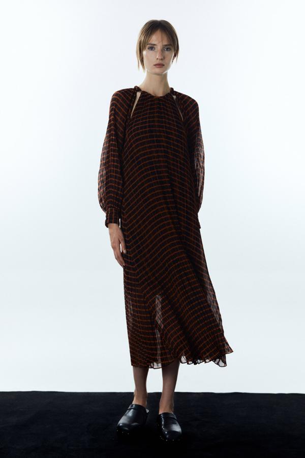 Vestido largo plisado con estampado de rayas naranjas sobre fondo negro. Mangas largas y fluidas con acabado en puño y aberturas en la parte de los hombros. Precio: 45,99 euros.