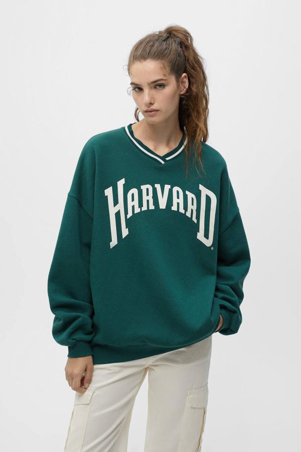 Esta sudadera de Pull&Bear es de color verde y tiene un gráfico de Harvard en contraste. 