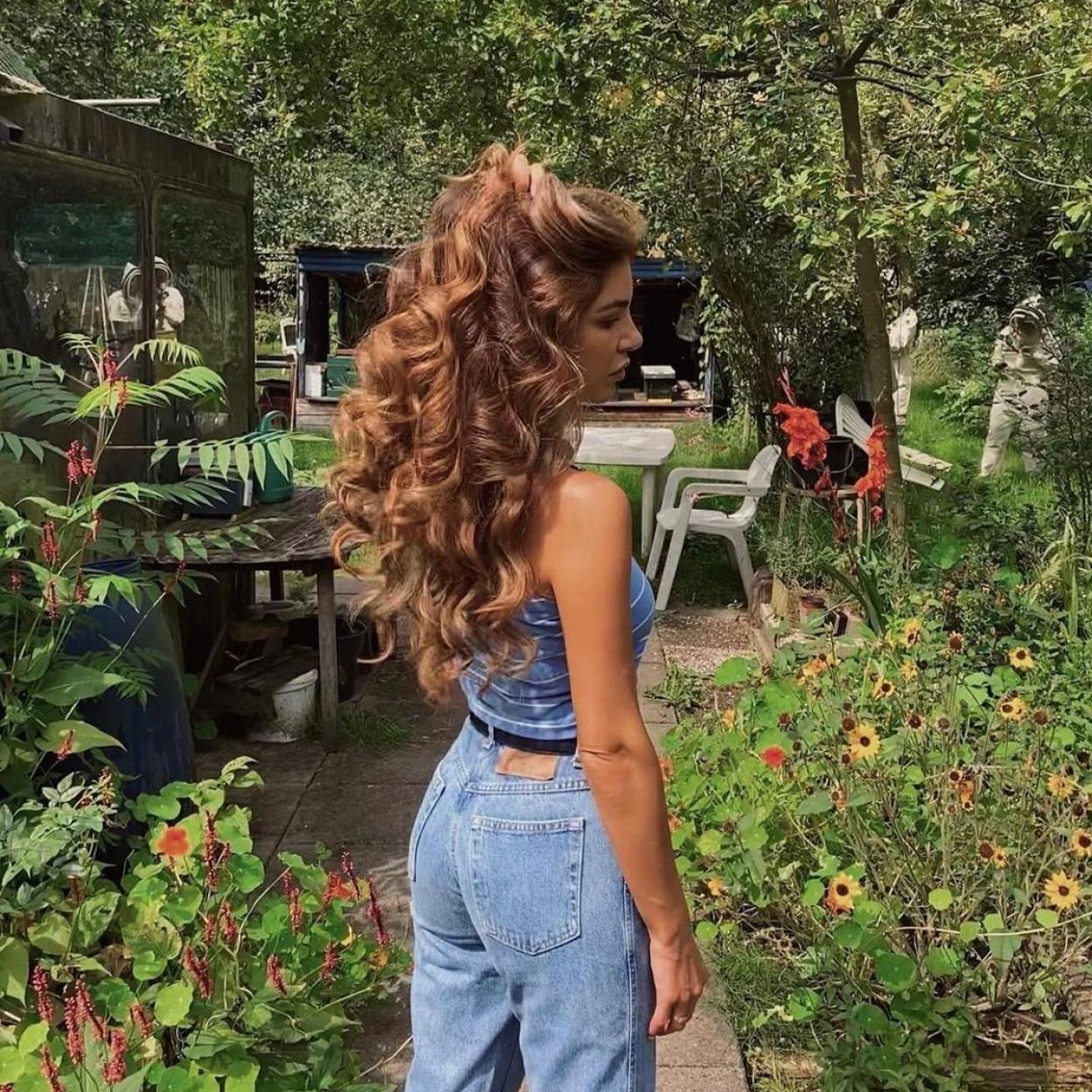 La influencer Negin Mirshalehi con unos vaqueros rectos y el pelo suelto y rizado.