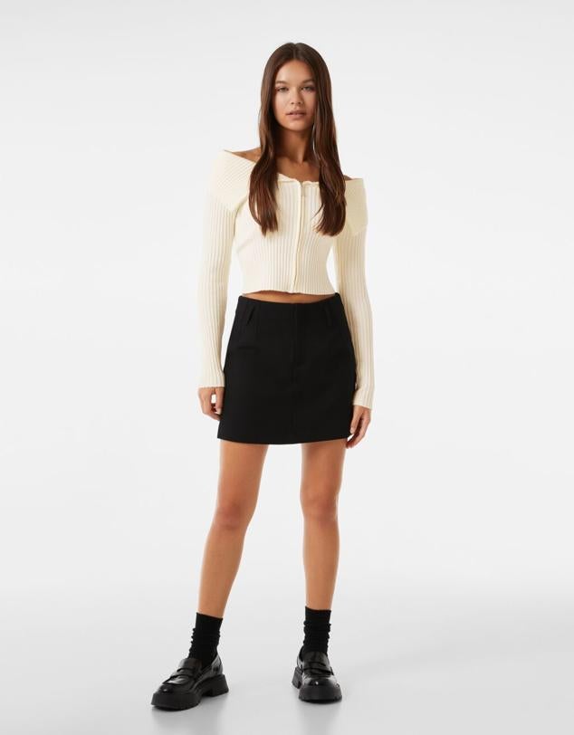 Chaqueta de punto con cremallera frontal y cuello bardot disponible en dos colores: crudo y negro. Precio: 19,99 euros en Bershka. Cómpralo aquí