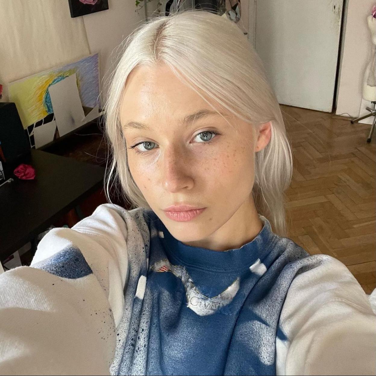 La influencer Faustyna Maciejczuk sin maquillaje posando con una sudadera blanca y azul.