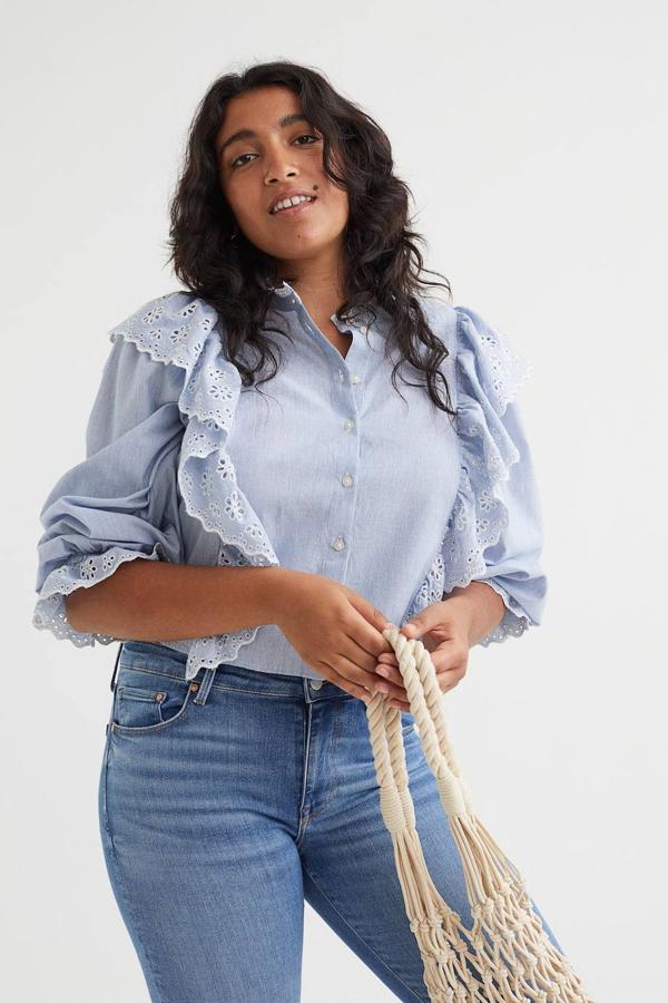 Blusa en tejido de algodón con cuello redondo, manga larga ligeramente abullonada, cierre de botones delantero y detalles de volantes con bordado inglés, en estampado a rayas azul claro, de H&M. Está disponible por 34,99 euros.