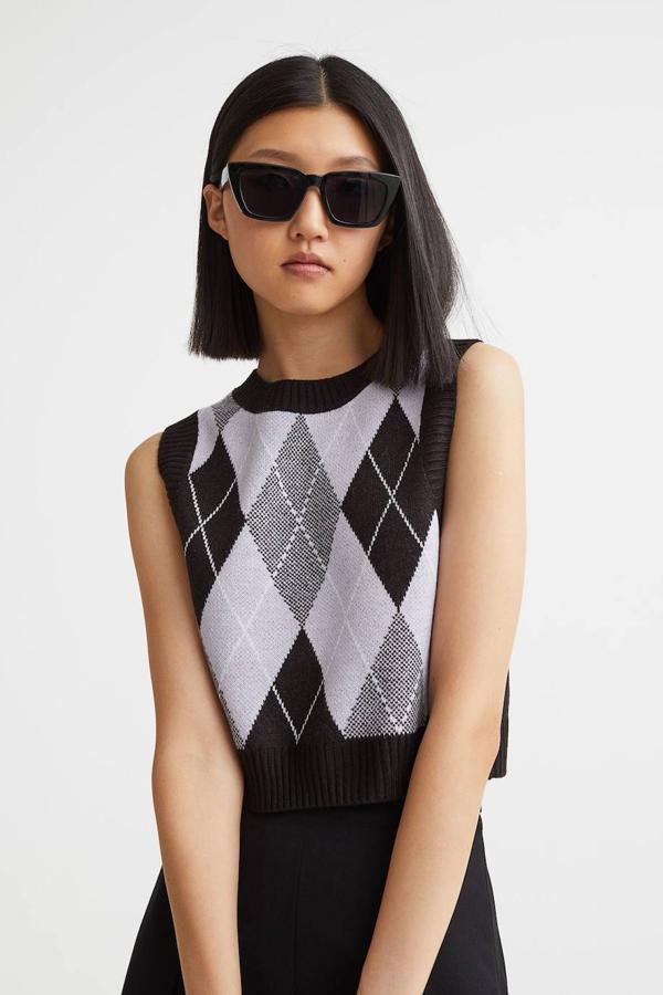 Chaleco de punto jacquard con diseño cropped, cuello redondo, manga sisa y terminaciones en canalé, con estampado de rombos color negro y lila, de H&M. Cuesta 14,99 euros.