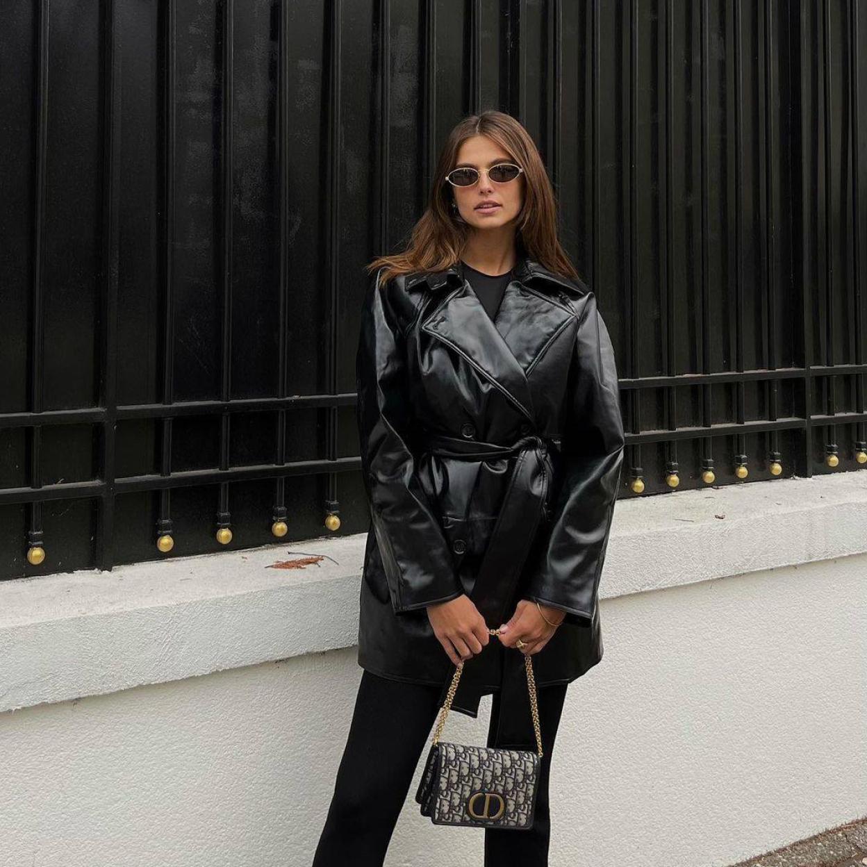 Influencer con un total look negro con trench corto en efecto piel al estilo de los 90