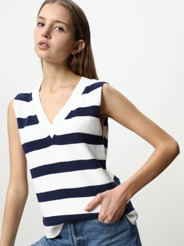 Chaleco de punto con corte holgado, cuello de pico y manga sisa amplia, confeccionado en tejido 100% algodón con estampado a raya en crudo y azul, de Lefties. Cuesta 12,99 euros.