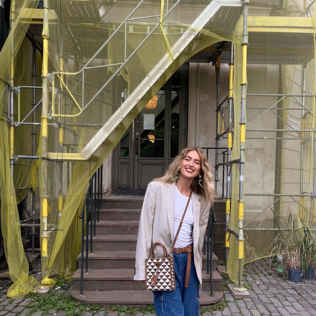La influencer Emili Sindlev vestida con un vaquero, una camiseta blanca y una blazer de piel.