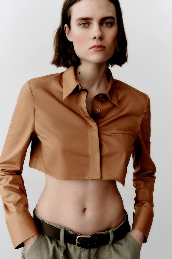 Camisa cropped de popelín con cuello solapa, manga larga acabada en puño, cierre delantero de botones y bolsillo de ojal en el pecho, color marrón claro, de Zara. Tiene un precio de 22,95 euros.
