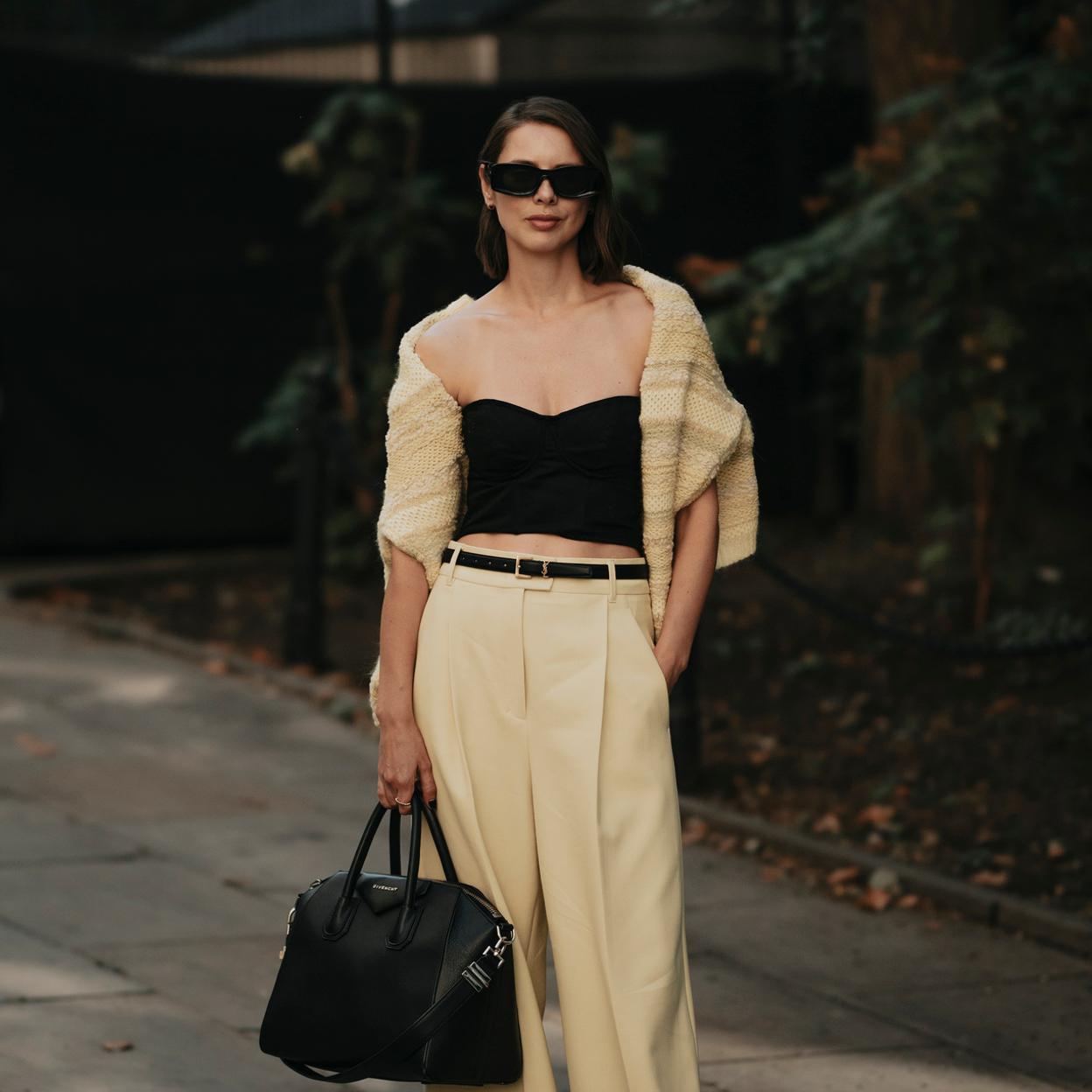 La influencer lleva un traje beige de chaqueta corta con un top negro. Completa el look con un bolso y unas gafas del mismo color. 