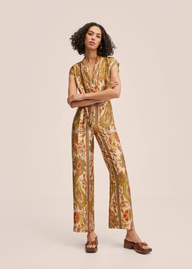 Mono largo con manga corta, escote de pico cruzado con solapa, perneras anchas y cinturón de lazada, en estampado paisley multicolor, de Mango. Su precio es de 49,99 euros.