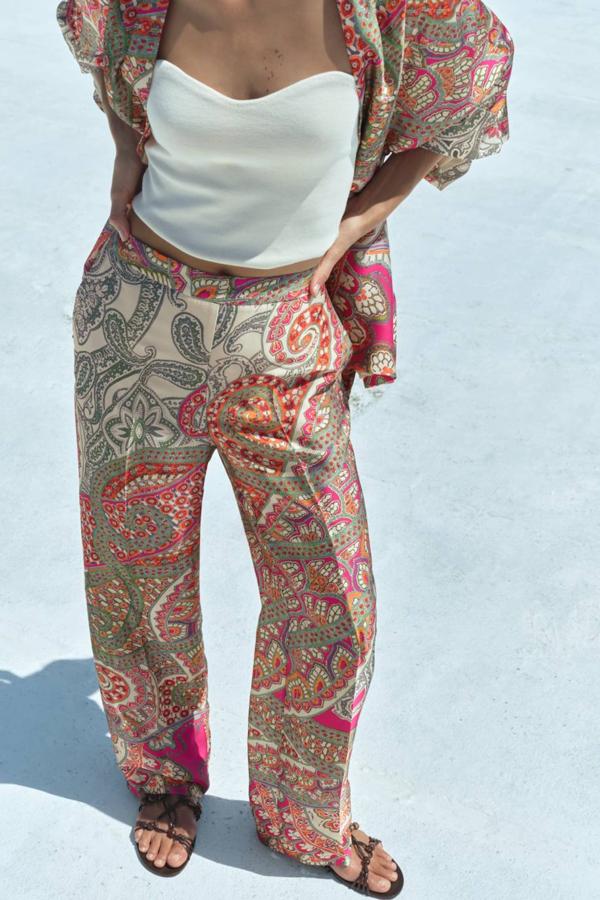 Pantalón largo con perneras anchas y rectas, tiro alto y raya marcada, en estampado paisley con tonos rosa, de Zara. Cuesta 29,95 euros.
