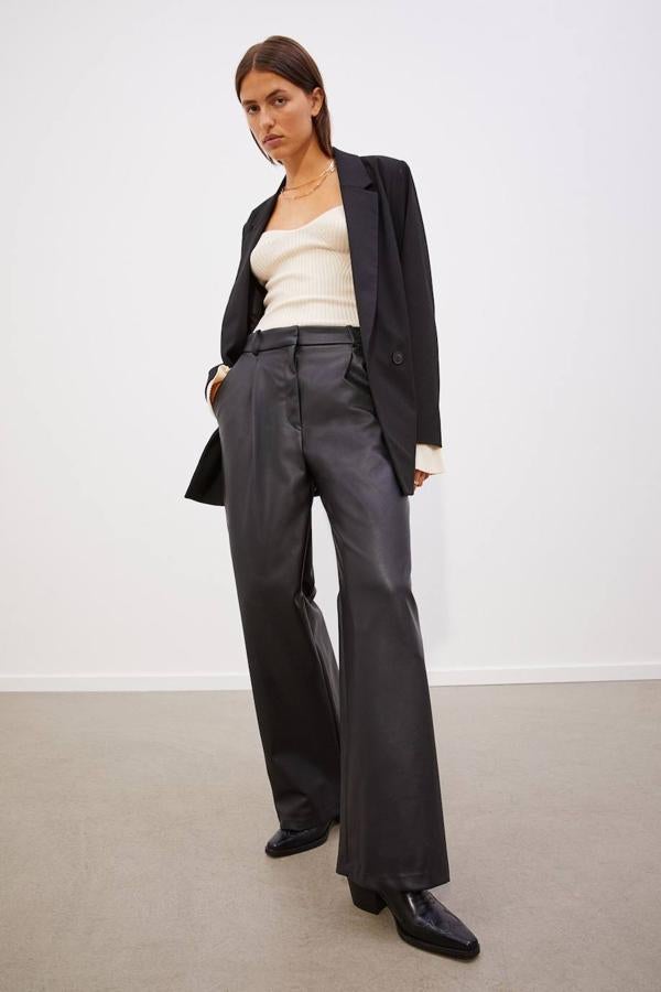 Pantalón largo efecto piel, con perneras rectas wide leg, tiro alto, bolsillos y detalles de pinzas, en negro, de H&M. Encuéntralo por 29,99 euros.