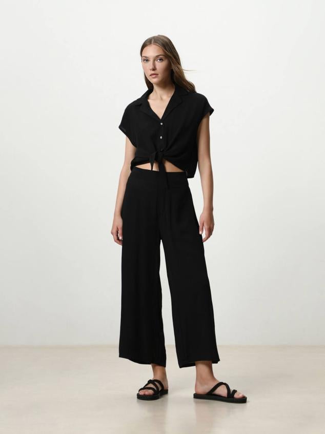 Pantalón fluido tipo culotte con perneras amplias y cropped, tiro alto y cintura elástica, en negro, de Lefties. Su coste es de 9,99 euros.