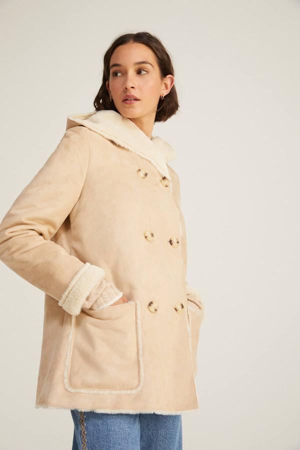 Chaqueta en tejido efecto piel soft con borreguillo a tono, cierre cruzado mediante doble botonadura frontal, manga larga, capucha y bolsillos de plastrón delanteros, color tostado, de Springfield. Está disponible a 69,99 euros.