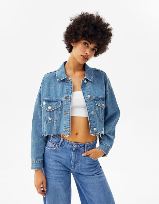 Cazadora vaquera de corte cropped con los bajos deshilachados y bolsillos con solapa en el delantero. Disponible en tres colores: azul lavado, azul claro y blanco. Precio: 25,99 euros. Cómpralo aquí