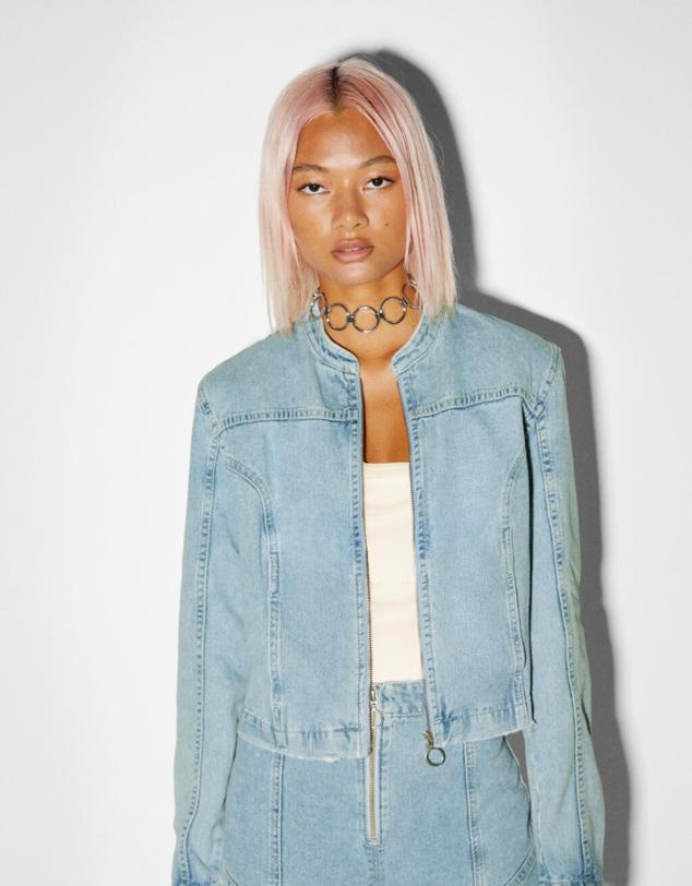 Sobrecamisa vaquera corta sin cuello y cremallera delantera. De color azul claro. Precio: 29,99 euros. Cómpralo aquí