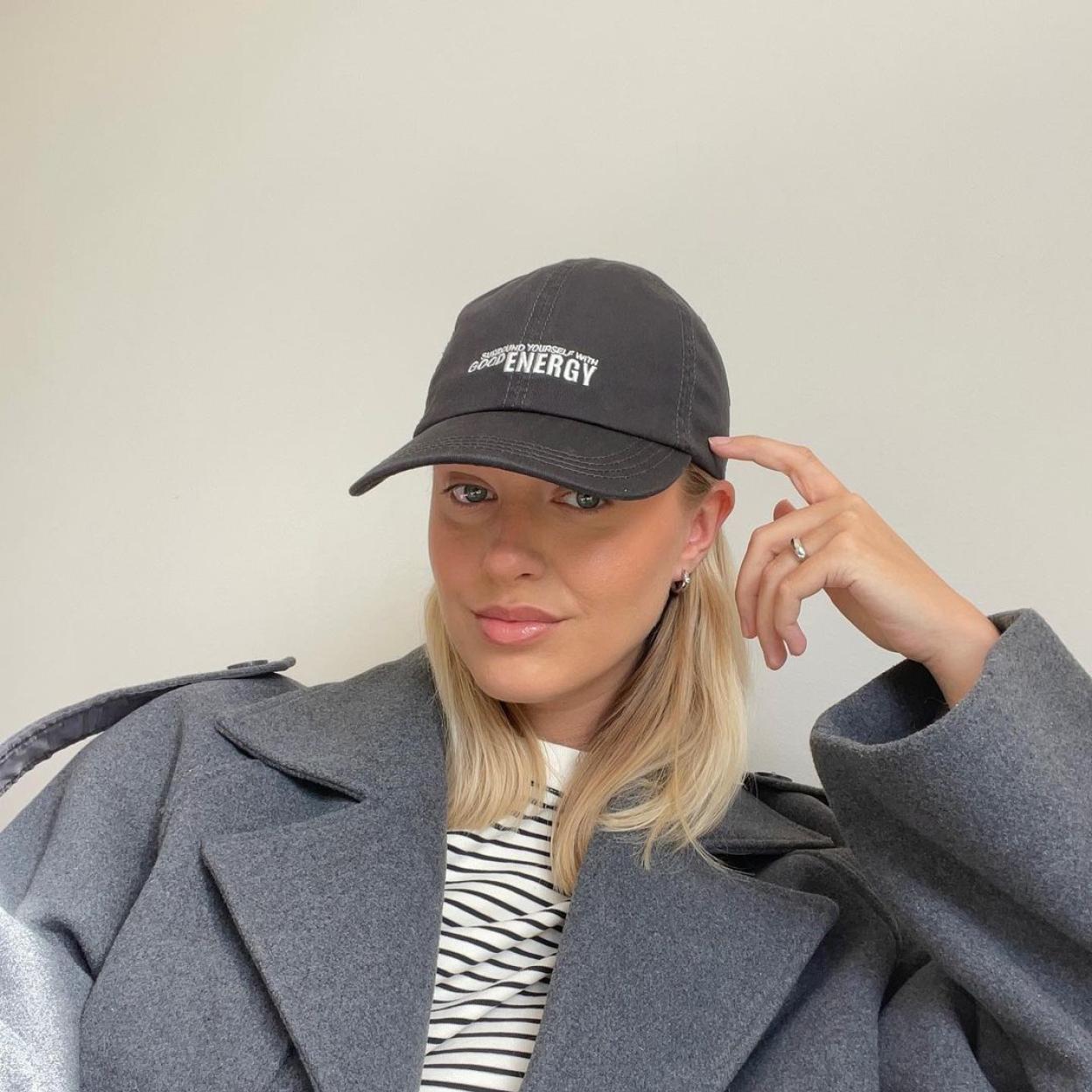 La influencer lleva una americana oversize que combina con una camiseta de rayas de manga corta y una gorra gris. 