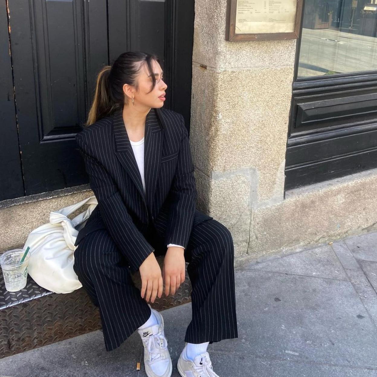 La influencer lleva un traje de raya diplomática que combina con un top blanco y unas zapatillas.