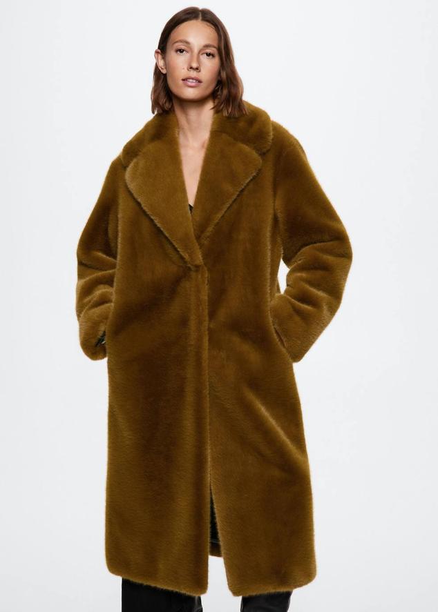 Abrigo largo de pelo con diseño oversize, cuello solapa con muesca, bolsillos delanteros y cierre de botón oculto, color mostaza amarronado, de Mango. Puedes comprarlo a 119,99 euros.