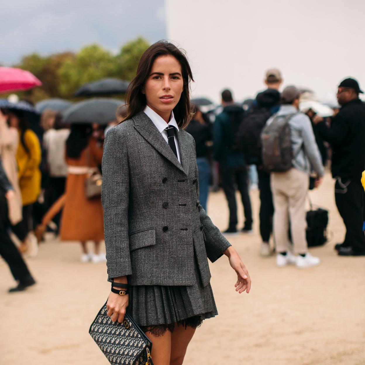 La influencer lleva un falda corta de tablas que combina con una americana entallada y unas botas altas. 