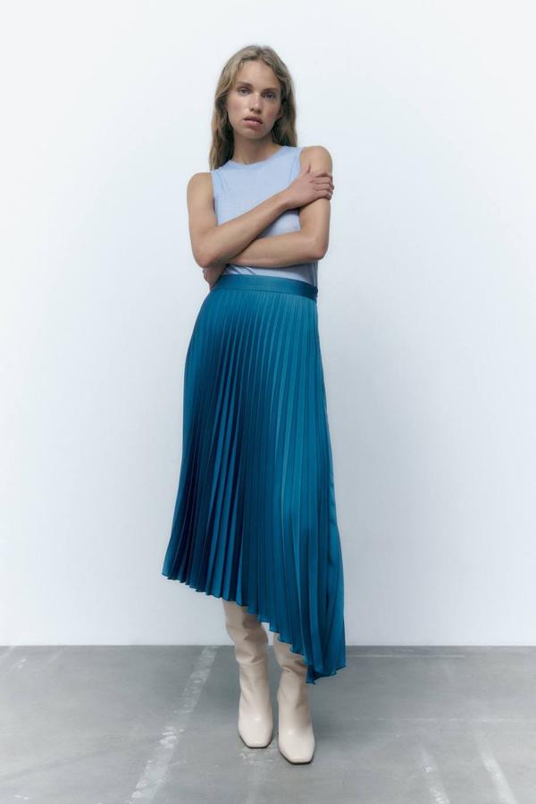 Falda midi plisada con tiro alto y bajo asimétrico, en tono azul acero, de Zara. Está disponible a 25,95 euros.