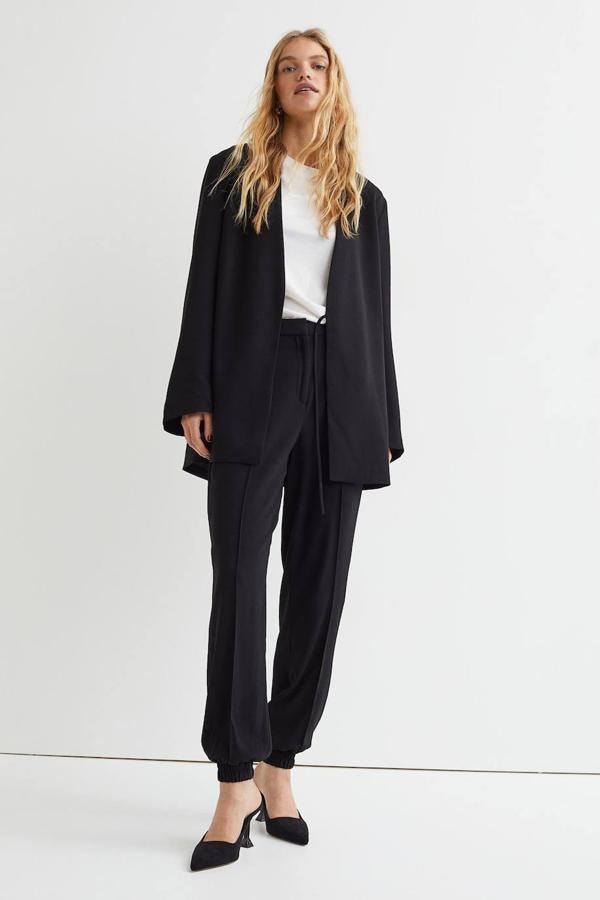 Pantalón jogger de vestir con talle alto, cintura elástica, raya marcada, perneras holgadas acabadas en puño y bolsillos, en negro, de H&M. Está disponible a 29,99 euros.