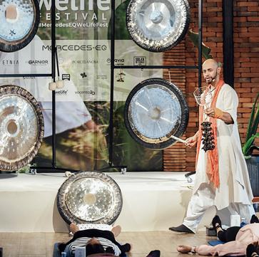 Imagen secundaria 1 - Silvia Cogost durante su ponencia, Nain con los gongs de la sesión de baños de sonido. Aitor Sánchez durante el transcurso de su charla.
