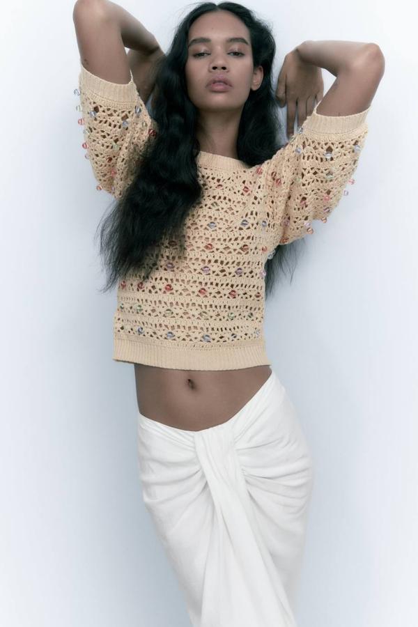 Jersey de punto crochet con manga corta, cuello redondo, detalles calados, terminaciones en rib y abalorios multicolor, en beige. Lo comprarás por 39,95 euros.