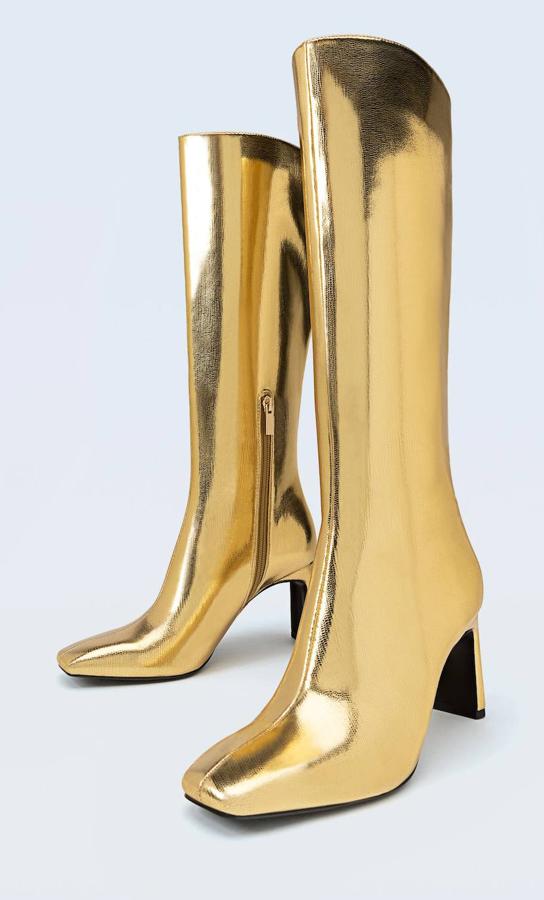 Botas altas en tejido efecto piel metalizado y texturizado, puntera redonda y tacón rectangular, color dorado, de Stradivarius. Tienen un precio de 59,99 euros.