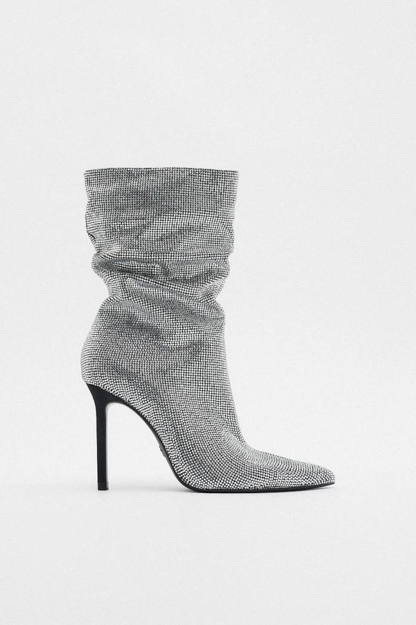 Botas de tacón alto y fino con caña arrugada y ancha, acabado en punta y detalle de aplicación de brillos, de Zara. Están disponible por 119 euros.