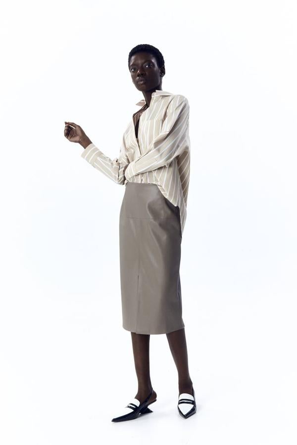 Falda midi en tejido efecto piel con corte recto, tiro alto y abertura, en tonos topo o negro, de Sfera. Está disponible por 25,99 euros.