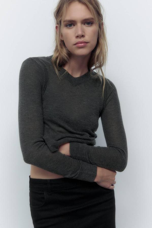 Jersey en tejido de punto fino entallado con cuello de pico y manga larga, color gris oscuro, de Zara. Hazte con él por 25,95 euros.