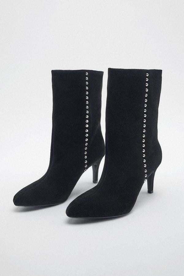 Botines en tejido de serraje con caña media y ancha, puntera redonda, tacón medio y detalle de aplicación de tachas metálicas en los laterales, de Zara. Están disponibles por 69,95 euros.