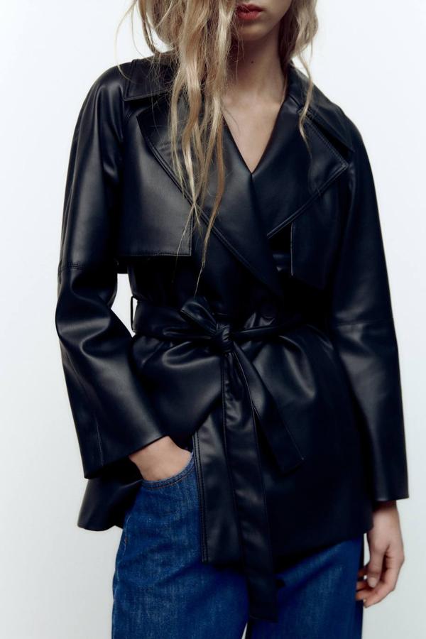 Blazer con diseño trench en tejido efecto piel, cuello solapa, amplio, manga larga y cierre cruzado con cinturón de lazada a juego, color negro, de Zara. Cuesta 59,95 euros.