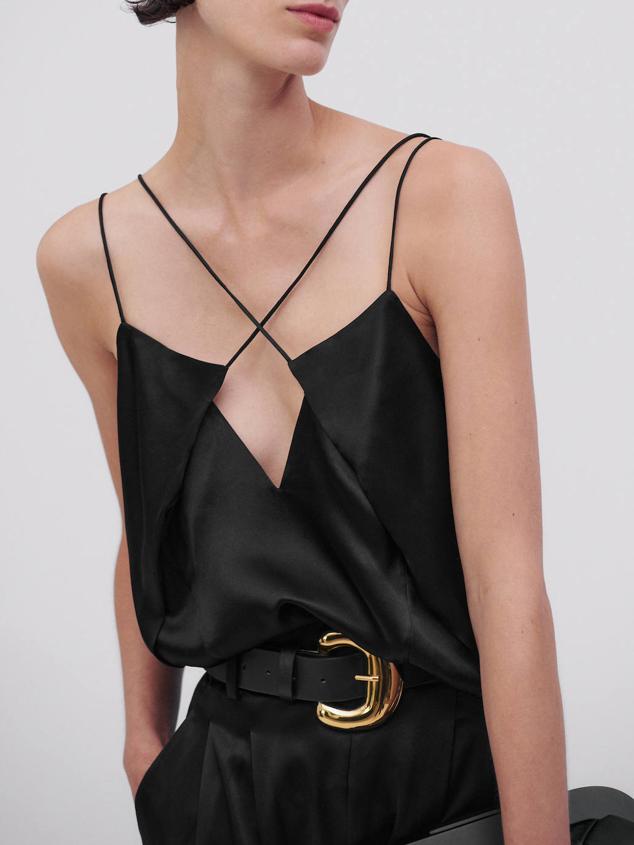 Top lencero en tejido satinado de seda con diseño asimétrico y doble tirante fino, color negro, de Massimo Dutti. Puedes encontrarlo a 69,95 euros.