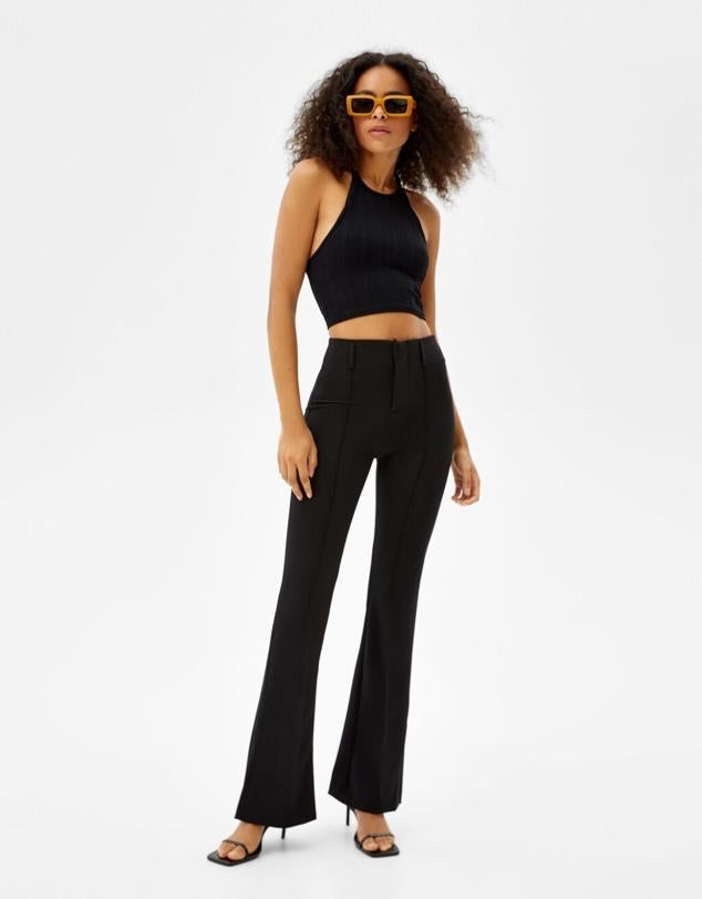 Pantalones negros básicos estilo flare de tiro alto y con hebillas en la zona de la cintura. Precio: 16,09 euros (antes 22,99 euros). Cómpralo aquí