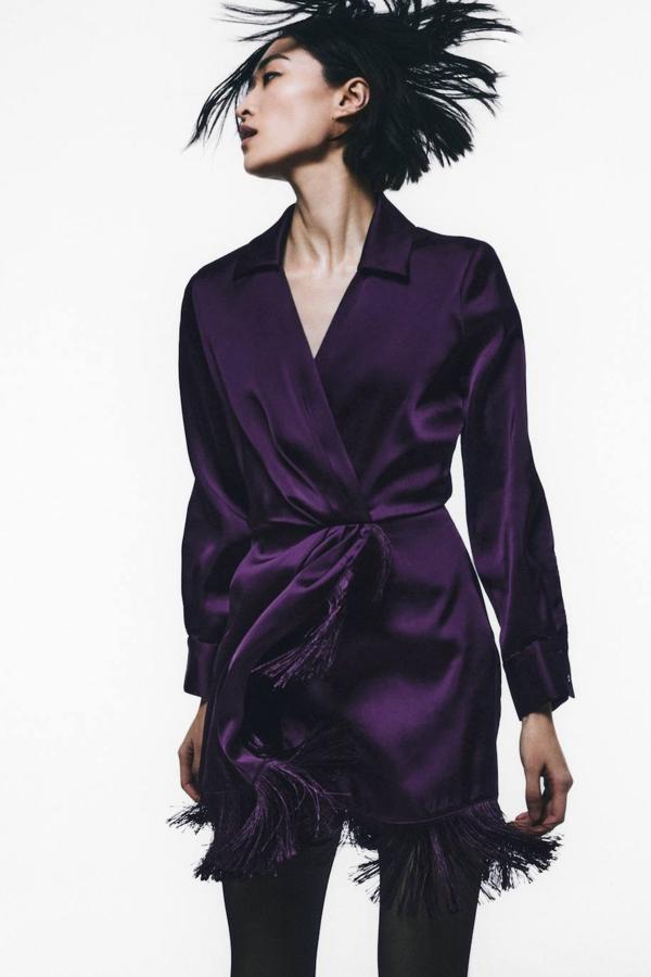 Vestido corto en tejido satinado con diseño cruzado, cuello solapa, manga larga y detalles de flecos a tono, en morado, de Zara. Hazte con él a 39,95 euros.