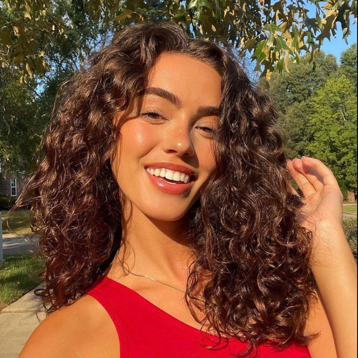 La modelo luce una melena rizada brillante y definida obtenida con una crema definidora de rizos