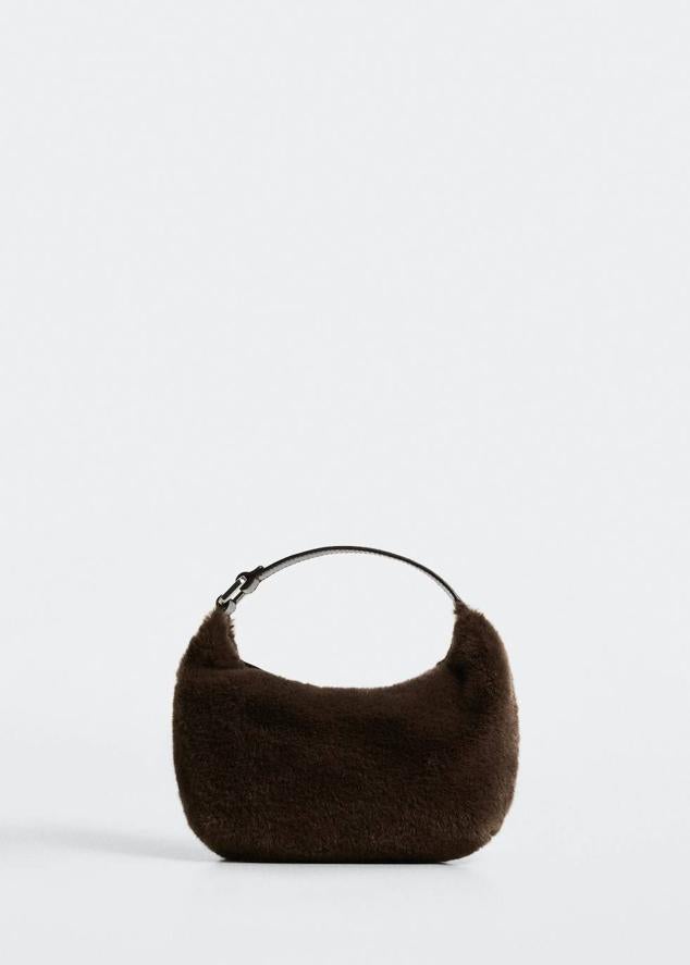 Bolso mediano con forma de media luna, asa corta, cierre de cremallera y tejido efecto pelo, en marrón oscuro, de Mango. Está disponible por 29,99 euros.